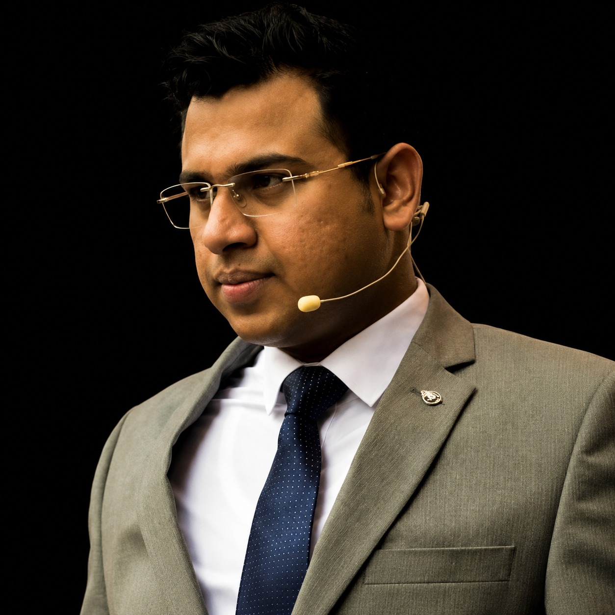 Anmol Pushjai Goel speaking on stage with a headset microphone